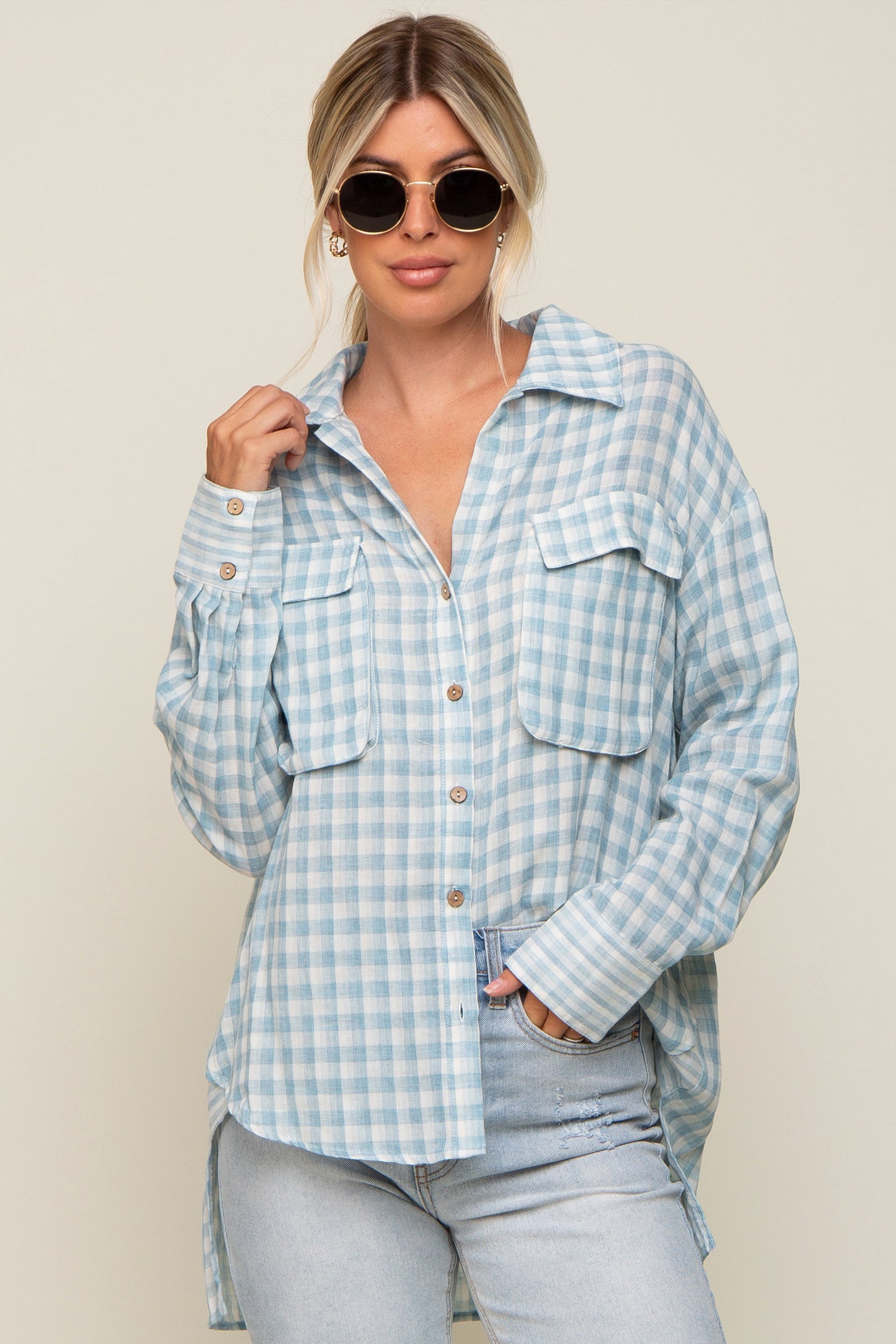 Woman wearing a light blue and white gingham button-down shirt and light wash denim jeans