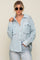 Woman wearing a light blue and white gingham button-down shirt and light wash denim jeans
