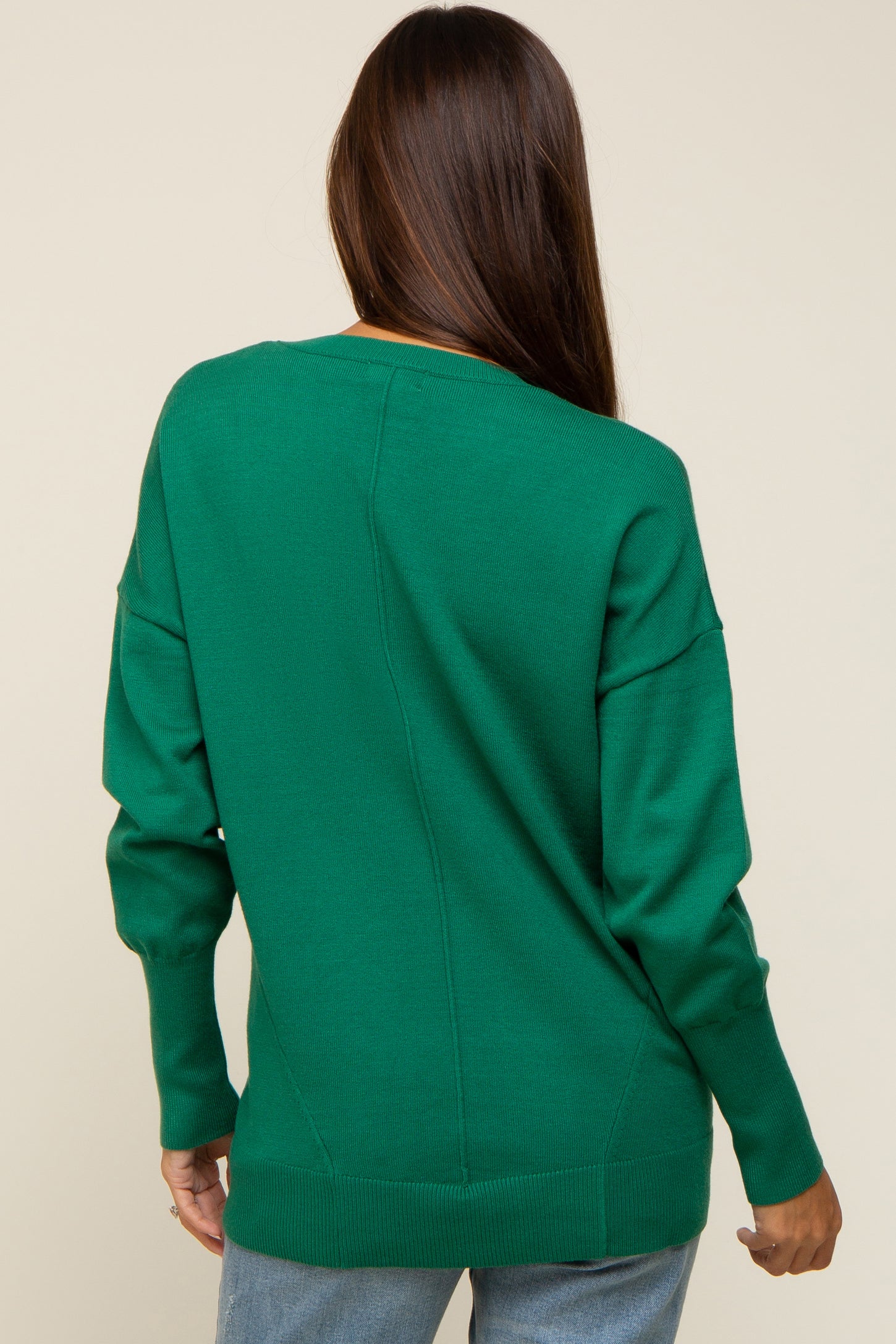 back view of a woman wearing a long sleeve emerald green knit sweater with drop shoulders