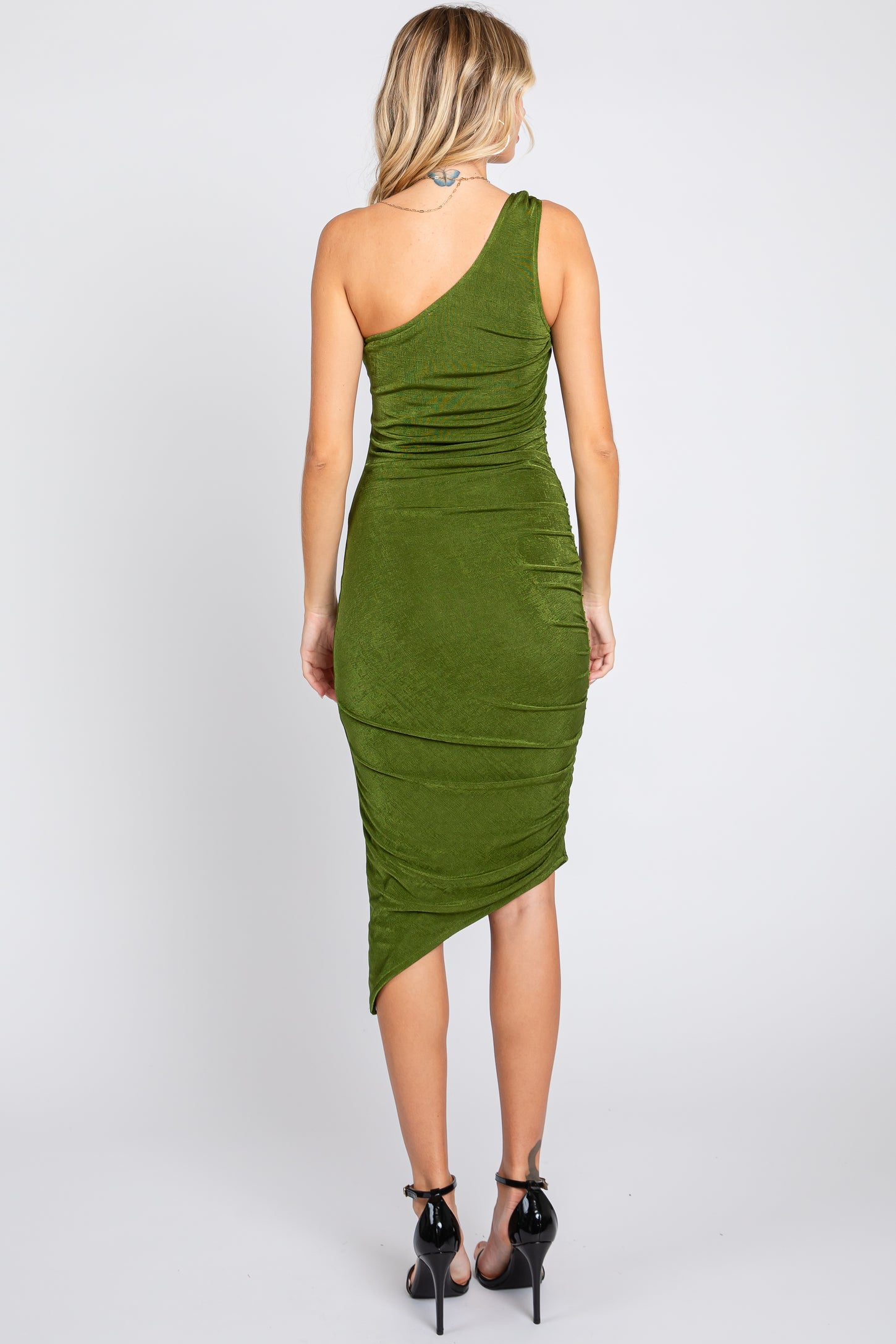 woman wearing a one-shoulder green midi dress with ruching details and a high-low hemline