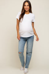 pregnant woman wearing a white maternity t-shirt and distressed blue jeans with white sneakers
