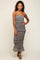 woman wearing a black floral tiered maxi dress with thin straps and ruffle details, standing and smiling