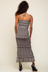 woman wearing a black floral print maxi dress with tiered ruffles, showing the back and a tattoo on her shoulder