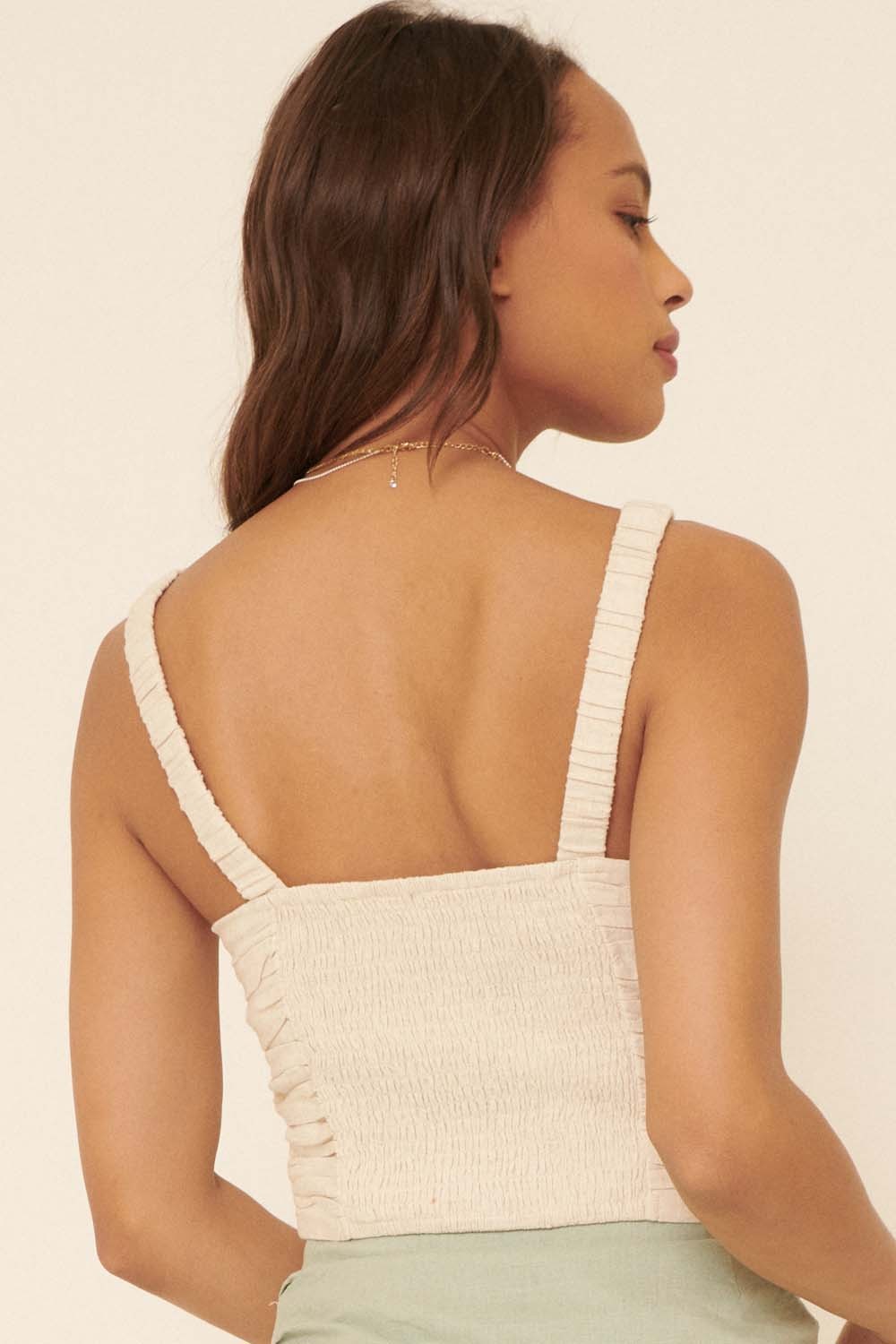 woman wearing a beige smocked crop top with thin straps, showing the back detail