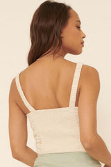 woman wearing a beige smocked crop top with thin straps, showing the back detail