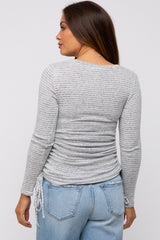 woman wearing a gray striped maternity top with side ruching and long sleeves, viewed from the back