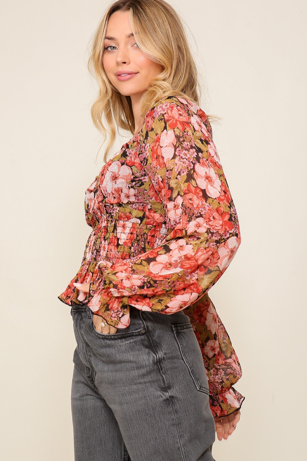 woman wearing a floral long sleeve blouse with gathered details and puffed sleeves paired with high-waisted jeans