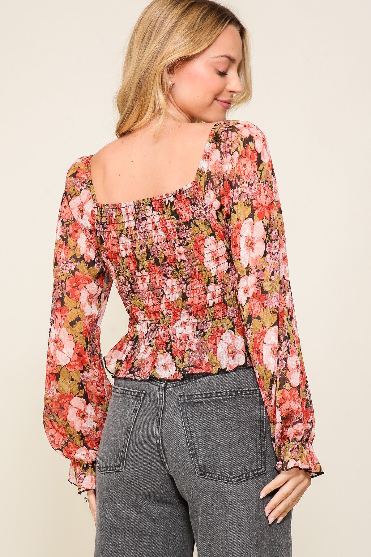 woman wearing a floral smocked blouse with long sleeves and a square neckline, styled with high-waisted jeans