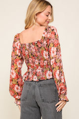 woman wearing a floral smocked blouse with long sleeves and a square neckline, styled with high-waisted jeans
