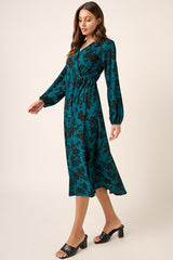 woman wearing a teal floral print long sleeve midi dress with a cinched waist and black heeled mules