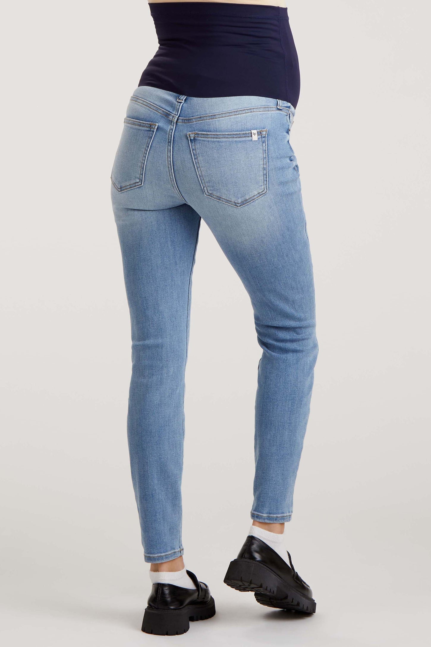 maternity wear light blue skinny jeans with a stretchy waistband, model showing a baby bump from the back