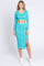 woman wearing a turquoise long sleeve cropped top and a matching midi skirt with a side slit
