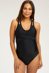 woman wearing a black maternity swimsuit with a cross front design and adjustable straps