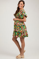 woman wearing a vibrant floral print maternity dress with short ruffled sleeves and a flowing skirt, highlighting her baby bump