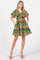 woman wearing a vibrant green floral short dress with puff sleeves and pockets, standing in a relaxed pose