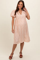 woman wearing a pink floral maternity dress with puff sleeves and a relaxed fit, showcasing her baby bump.