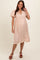 woman wearing a pink floral maternity dress with puff sleeves and a relaxed fit, showcasing her baby bump.