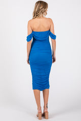 woman wearing a bright blue off-the-shoulder bodycon dress with ruched details and a mid-length hem