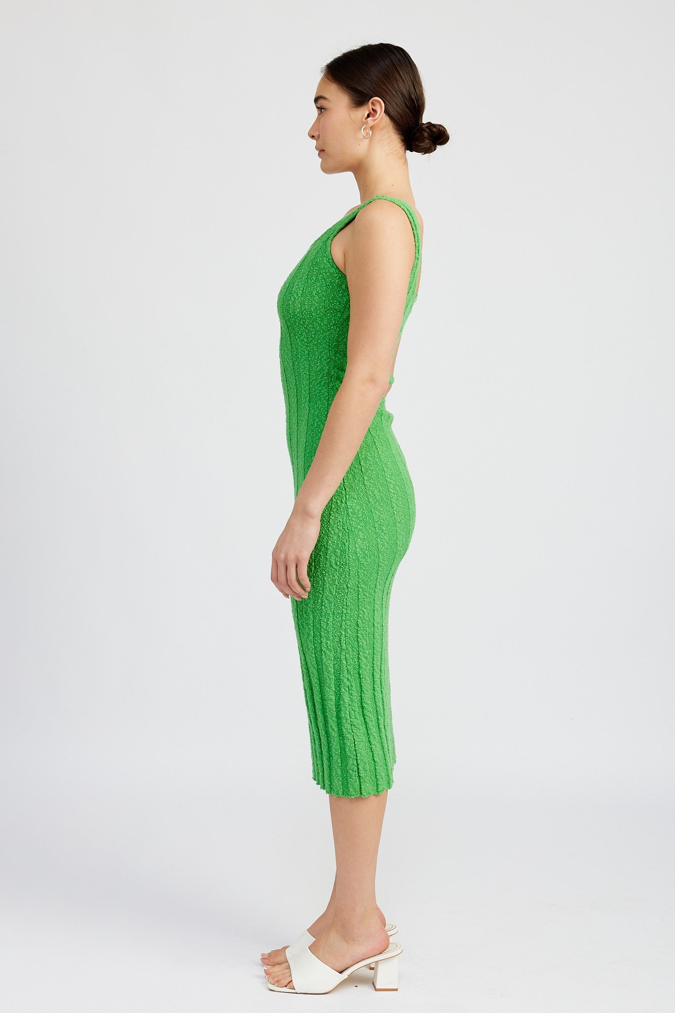 woman wearing a form-fitting green knitted midi dress with a ribbed texture and spaghetti straps