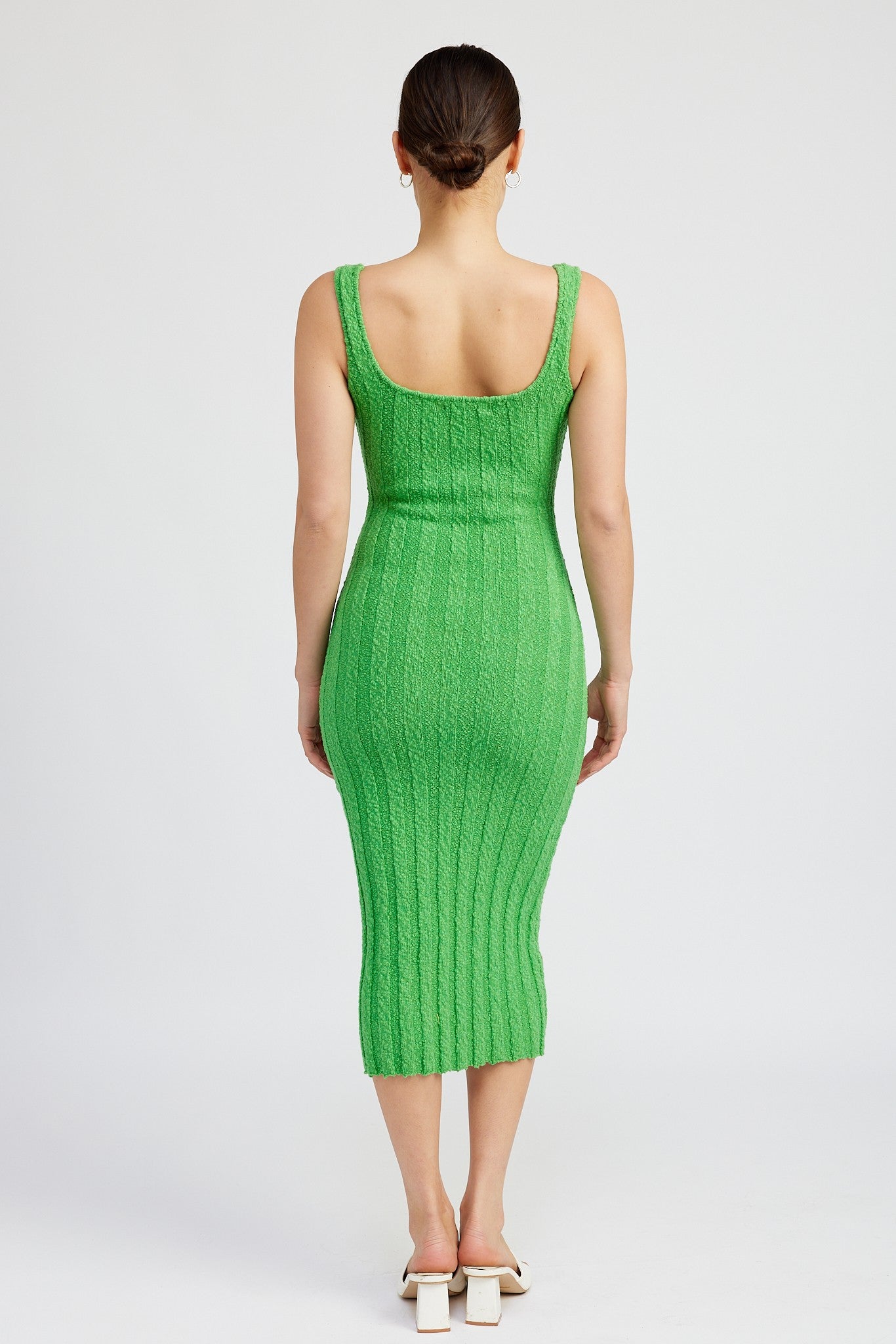 woman wearing a fitted bright green ribbed midi dress, showing the back view and a scooped neckline