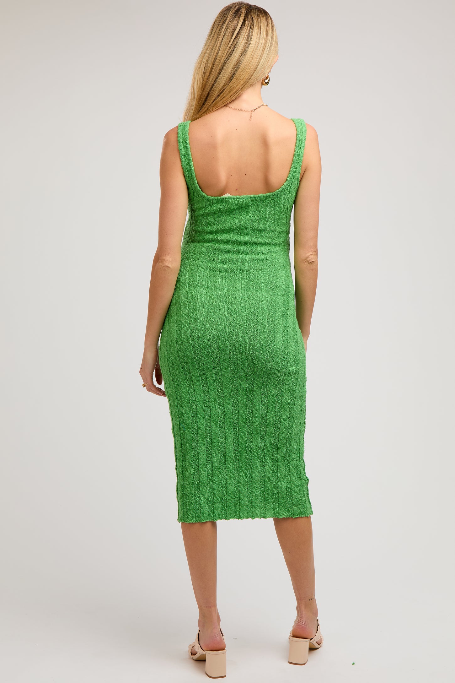 woman wearing a medium green ribbed knit maternity dress with a midi length and scoop back