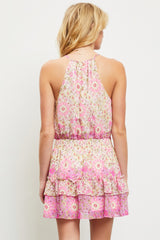 woman wearing a pink floral halter dress with a tiered ruffle hem, showing the back view