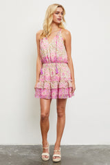 woman wearing a pink floral sleeveless dress with a ruffled hem and adjustable straps, standing on a gray floor